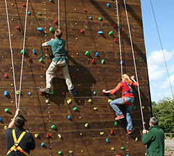 A man and woman climbing a rock climbing wall