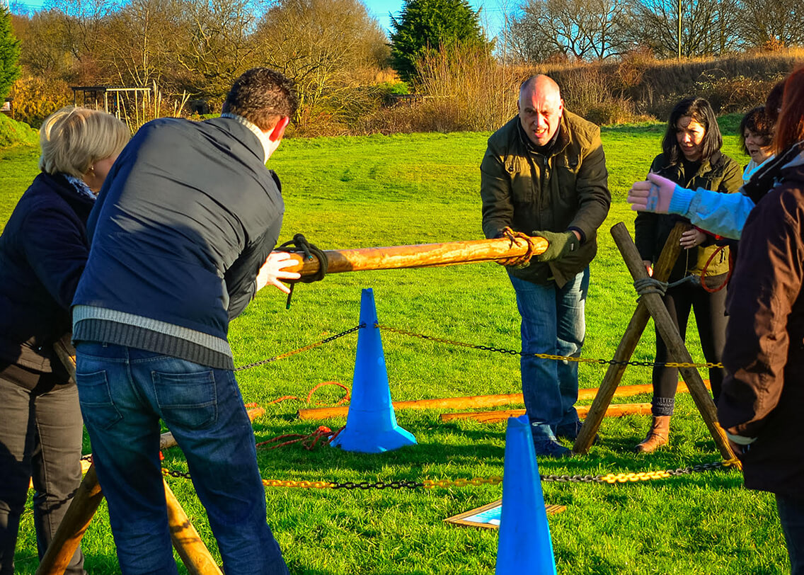 A group trying to cross platforms together using planks of wood