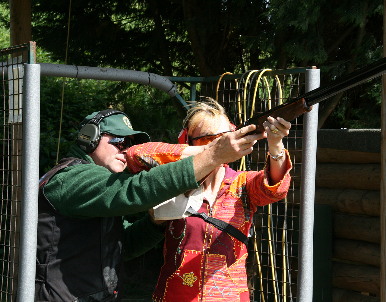 A woman being taught how to fire a shotgun